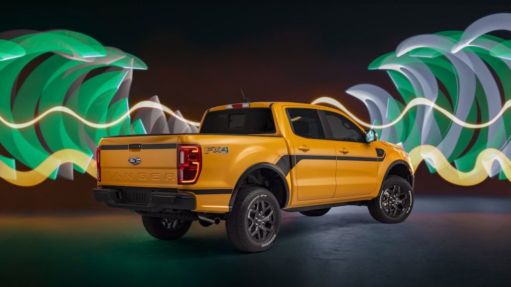 A photo of an orange 2022 Ford Ranger taken from the trunk side. The image is photoshopped with some light effects in the background.