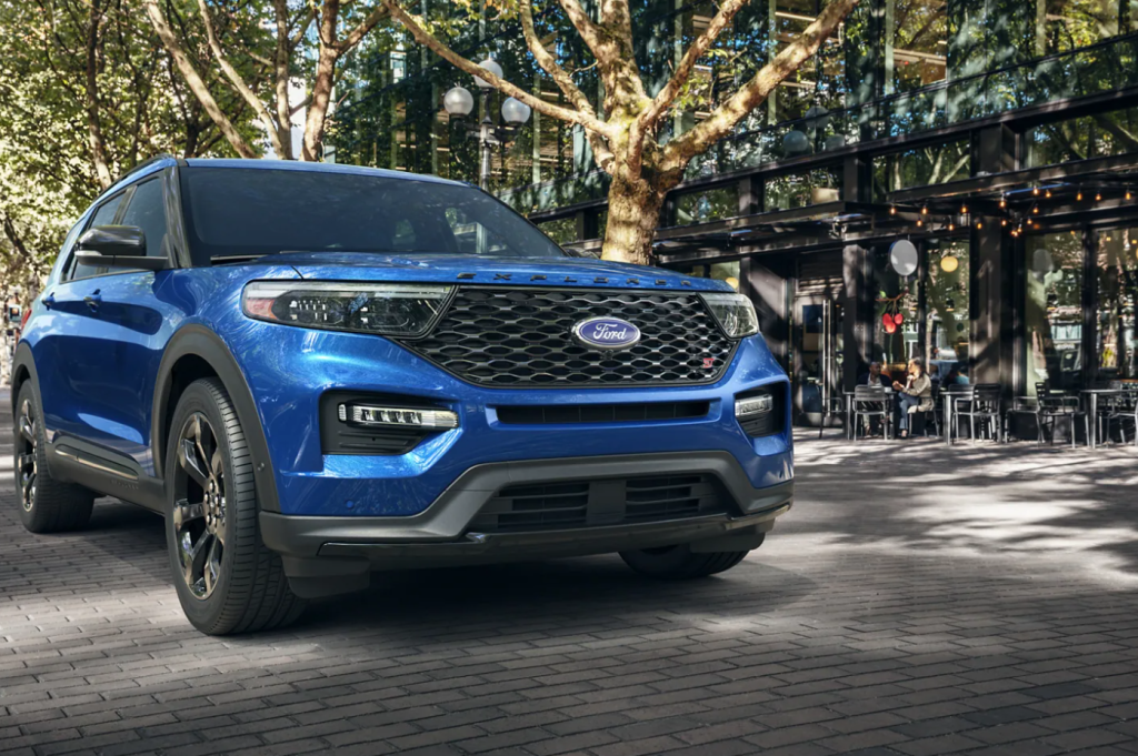 A blue 2022 Ford Explorer parked in front of a shaded city sidewalk.