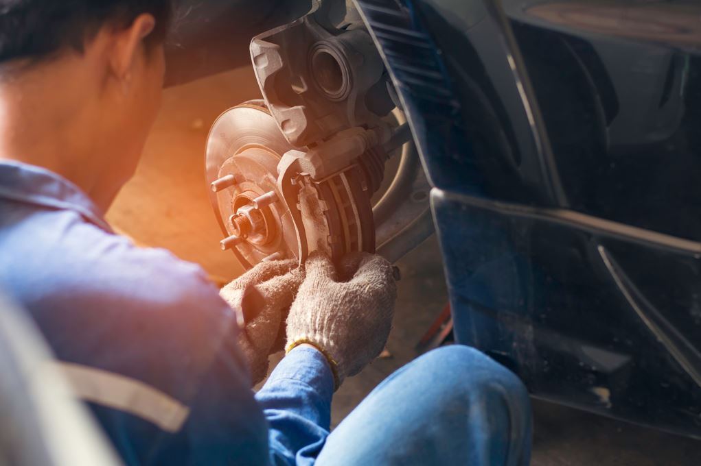 An auto technician working on the brakes of a car.