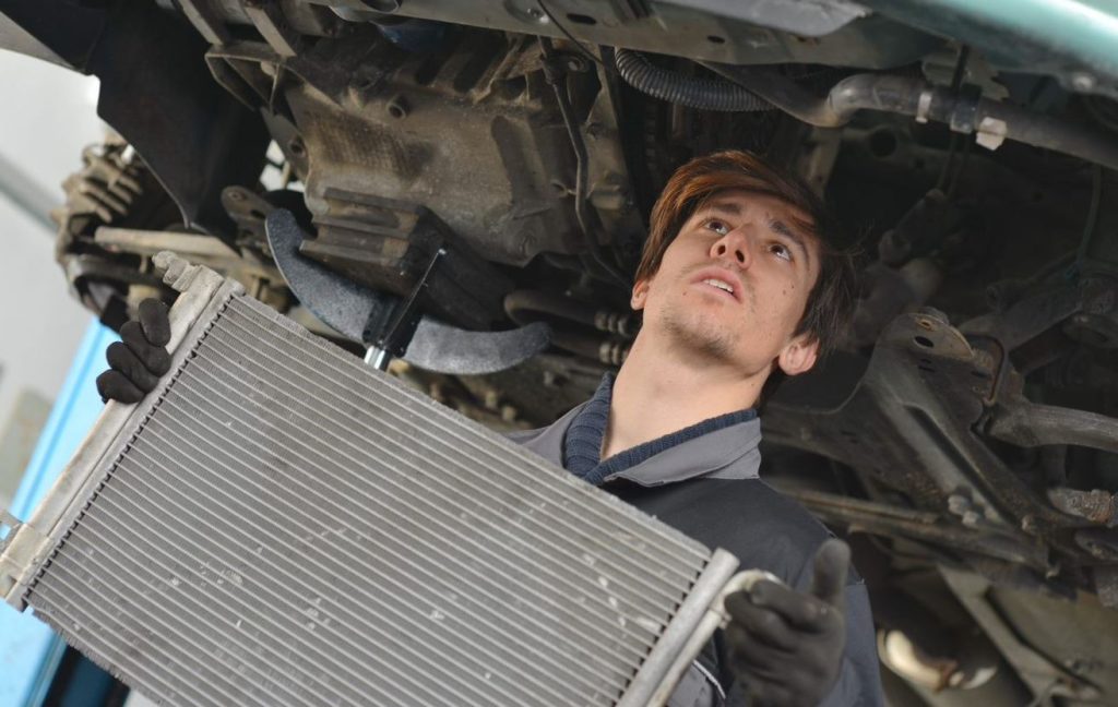 Vehicle technician replacing a radiator.