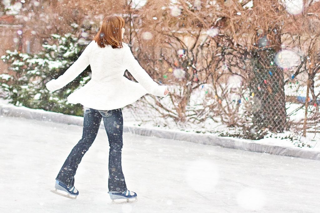A woman is ice skating on a rink.