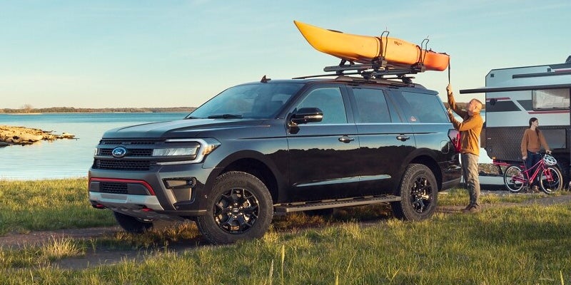 A black 2024 Ford Expedition with a yellow canoe strapped on top.