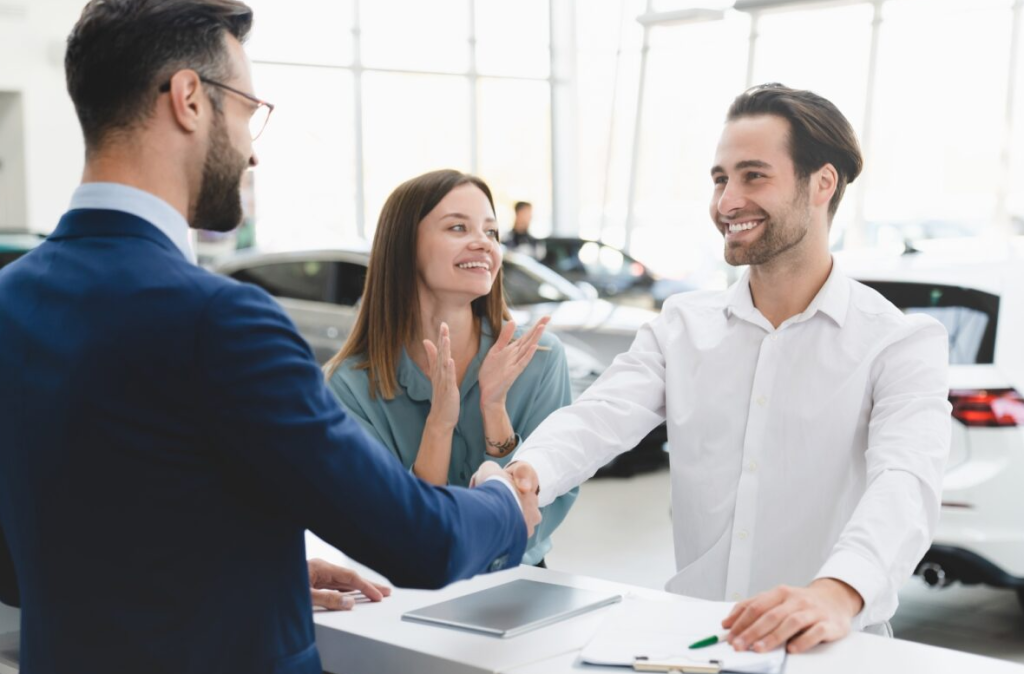 A couple shaking the car salesman's hand after financing their new vehicle.