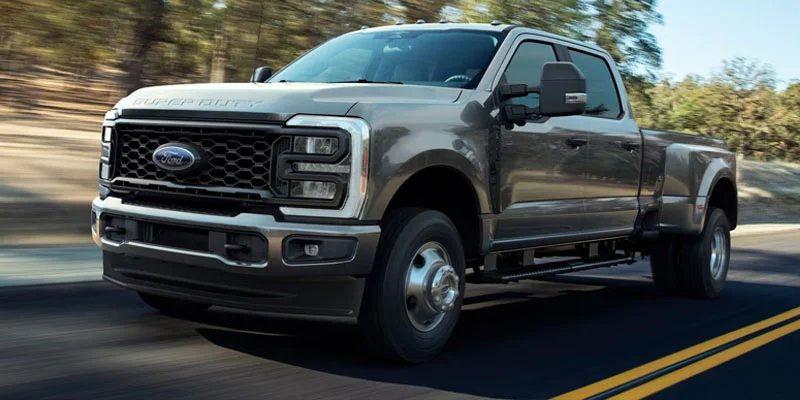 A Ford Super Duty pickup truck driving on a highway with a rugged landscape in the background.