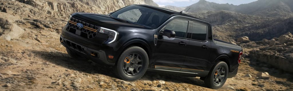 Black Ford Ranger Tremor pickup truck driving through rocky terrain